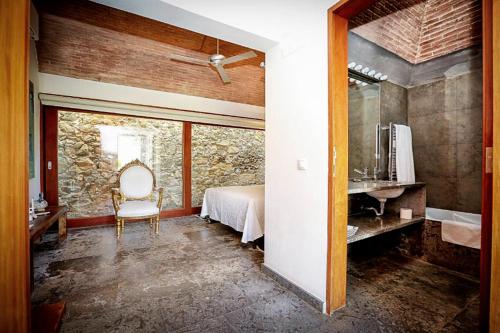 a bedroom with a bed and a chair in a room at Forte De Sao Joao Da Barra in Cabanas de Tavira