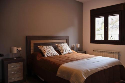 a bedroom with a bed with two pillows and a window at Apartamentos Aldeas de Pontones in Pontones