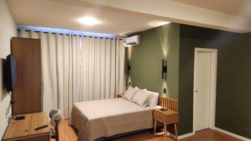 a bedroom with a bed and a television in it at Studio Cotia Próximo ao Thermas da Mata, Animalia Park e CT São Paulo in Cotia