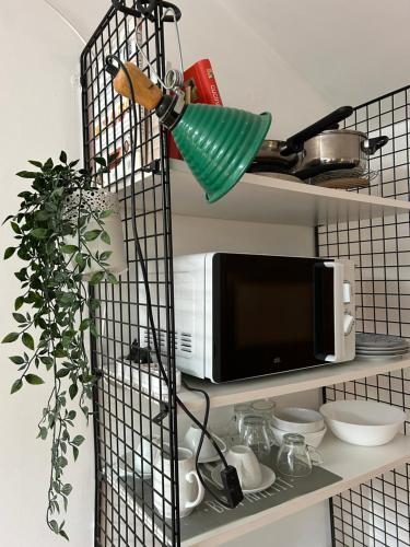 a black wire rack with a microwave on a shelf at A Modo Mio - Monolocale - Zona Stadio Ospedale Maggiore in Bologna
