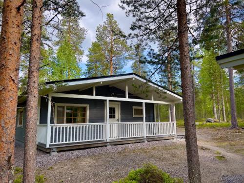 a house with a porch in the woods at Riekonsoppi, two bedroom private cabin in Pyhätunturi