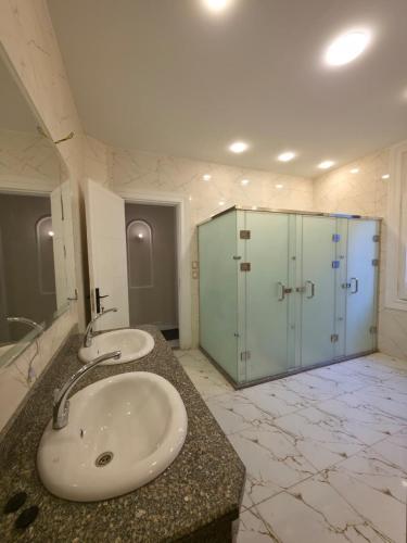 a bathroom with two sinks and a glass shower at Swisstay Downtown Cairo in Cairo