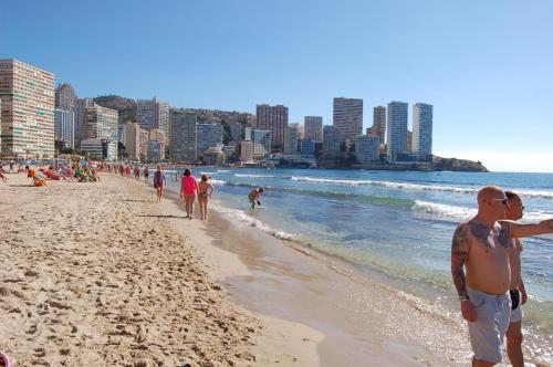 a group of people walking on the beach at My Pretty Payma Apartamentos in Benidorm