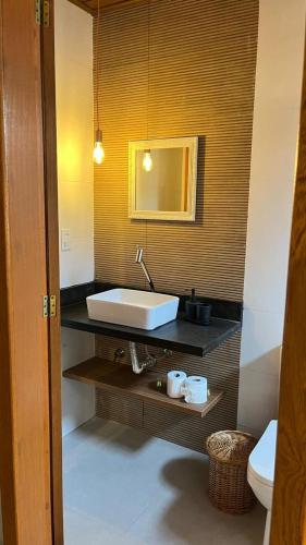 a bathroom with a white sink and a mirror at Vila Florença Chales in Santa Teresa