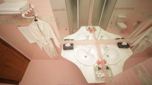 a pink bathroom with two sinks and a toilet at Four Squares by WIH in Karachi