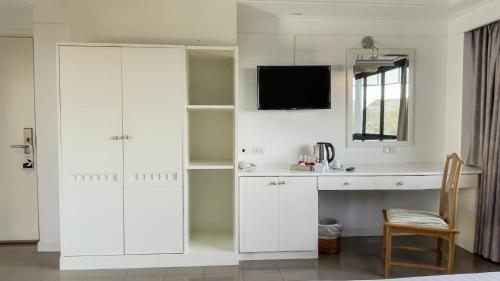 a white kitchen with a desk and a mirror at Rua Rasada Express in Trang