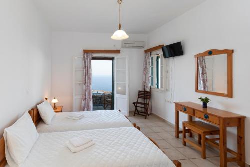ein Schlafzimmer mit zwei Betten, einem Schreibtisch und einem Fenster in der Unterkunft Spitha Sifnos in Artemonas