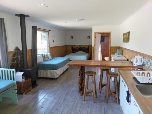 a kitchen with a table and a room with two beds at Cabaña Lefuco, Curacautin in Manzanar