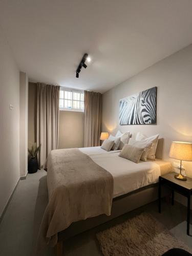 a bedroom with a large bed with a painting on the wall at Carmen Rooms -- Boutique B&B by the sea in Nerja