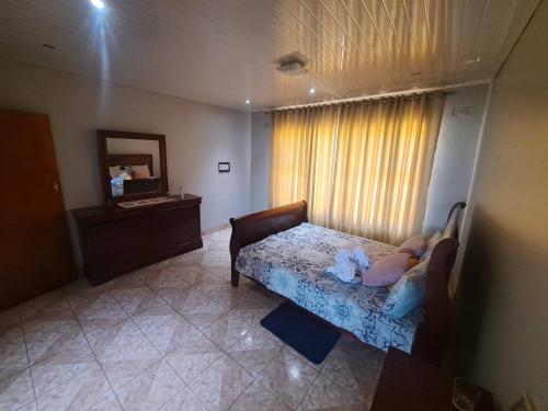 a bedroom with a bed and a mirror and a window at Bulawayo Bliss - Cozy 3 Bedroom House in Bulawayo
