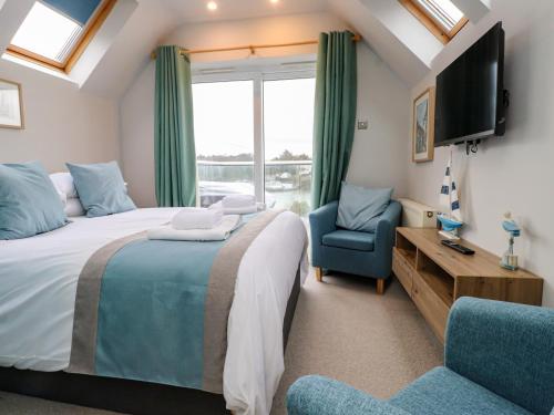 a bedroom with a bed and a tv and a chair at Alltwen in Porthmadog