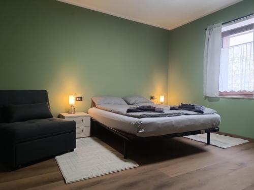 a bedroom with a bed and a couch and a window at Alexander Lodge in Isolaccia