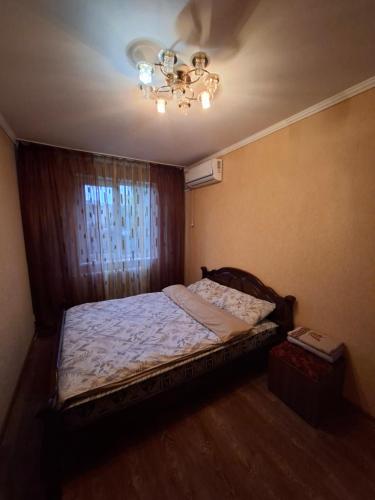a bedroom with a bed with a chandelier and a window at Терновской район in Kryvyi Rih