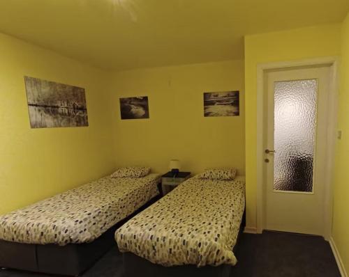 two beds in a room with yellow walls at Le chant des sirènes in Mettet