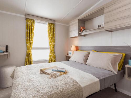 a bedroom with a large bed and a window at Riverside Essential Clover Caravan Pet 1 in Wooler