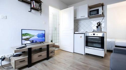 a living room with a kitchen with a tv on a table at T2 Calme proche de la citadelle in Arras