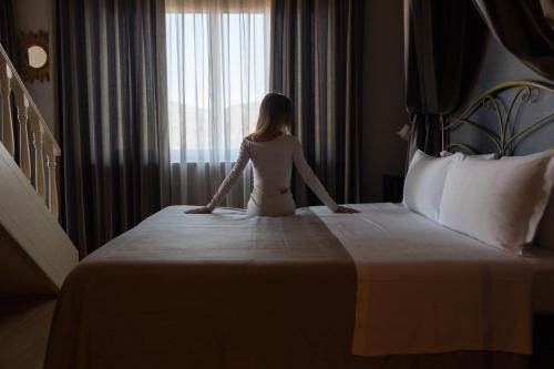 a woman sitting on a bed in a hotel room at Hotel Continental in Turin
