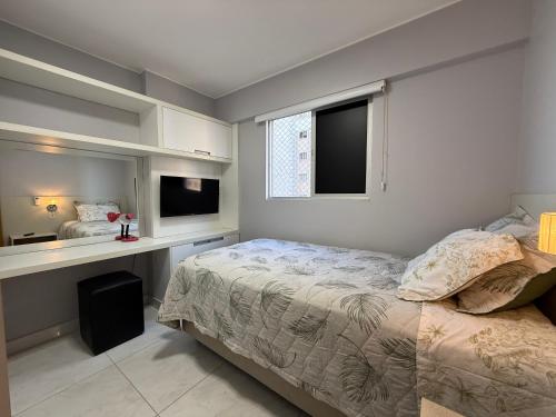 a bedroom with a bed and a desk and a window at Lindo Apartamento in Brasília