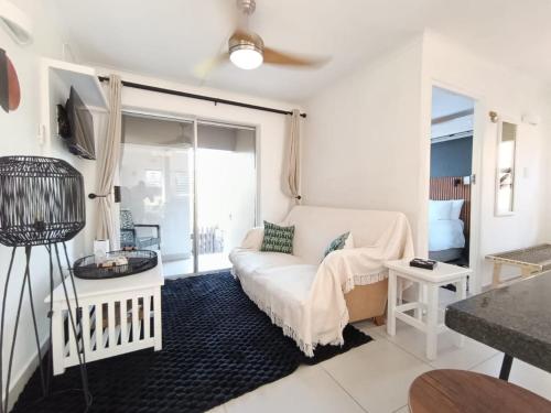 a white living room with a couch and a window at Cosy Beach Cottage 52 Chaka's Rock Chalets Resort in Ballito