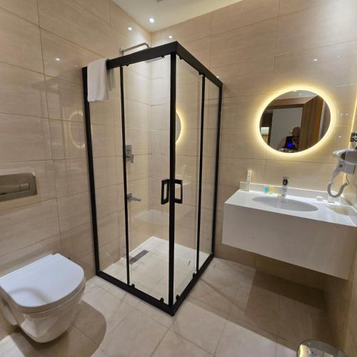 a bathroom with a shower and a toilet and a sink at BAZ Hotel Airport Road in Baghdād