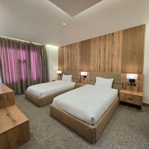 a hotel room with two beds and two tables at BAZ Hotel Airport Road in Baghdād