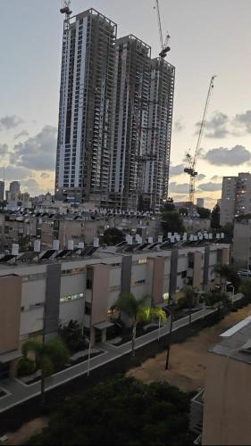 a view of a city with tall buildings and cranes at Small cozy room in a duplex in Bat Yam