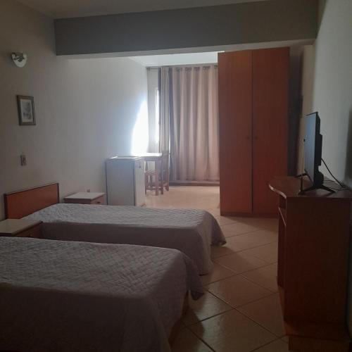 a hotel room with two beds and a flat screen tv at Village Hotel in São Borja