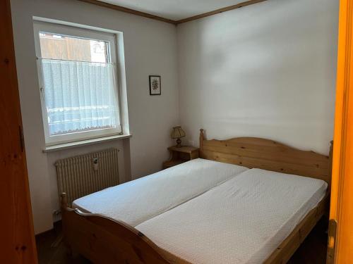 a bedroom with a bed and a window at Bilocale Casa Canazei in Alba di Canazei