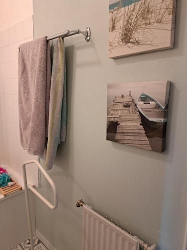 a bathroom with a towel rack and a picture of a pier at Petite Chambre CHEZ MARINA in Chantepie