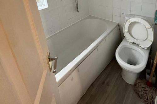 a bathroom with a toilet and a tub with a toilet seat up at 3 Bed House Sleeps 5 - Free Parking - Tv & WiFi in Sheffield