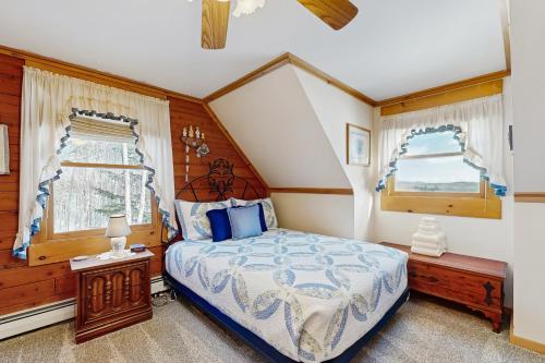 a bedroom with a bed and two windows at North Hill Cabin in Jay