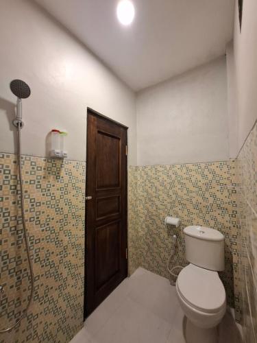 a bathroom with a toilet and a wooden door at Waceno Umma in Ruteng