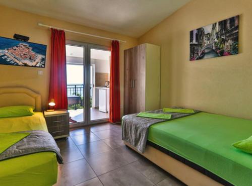 a bedroom with two beds and a balcony at Beachfront Sunset Apartments Sutomore in Brca