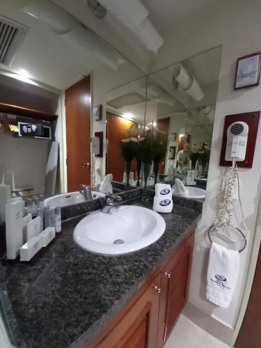 a bathroom with a sink and a large mirror at HOTEL ALTAMIRA SUITES in Caracas