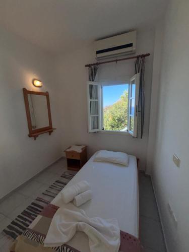 a small bedroom with a bed and a window at Sunset Studio Apartments in Kalymnos