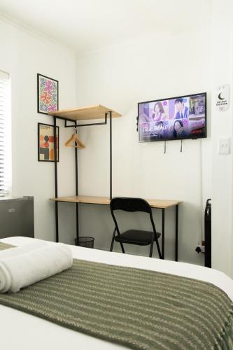 a bedroom with a bed and a desk and a tv at Foools Inn - Trendy Rooms available in the Heart of Sea Point! in Cape Town