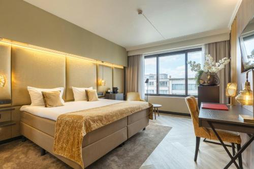 a hotel room with a bed and a desk at Leonardo Hotel Antwerp The Plaza in Antwerp