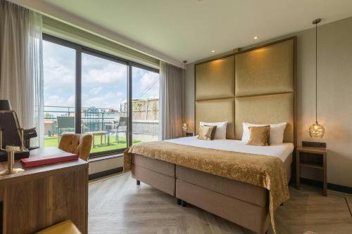 a bedroom with a large bed and a large window at Leonardo Hotel Antwerp The Plaza in Antwerp