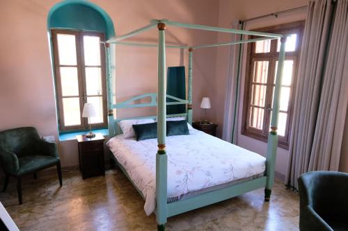 a bedroom with a four poster bed and two windows at Spiritu in Ḩārat al Qal‘ah