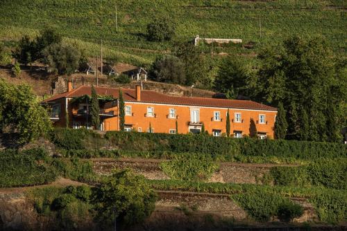 a large orange house on a hill with bushes at Quinta do Vallado - Douro Wine Hotel in Peso da Régua