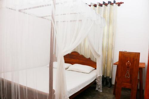 a bedroom with a canopy bed with white curtains at Ivy Cottage- Midigama in Midigama East