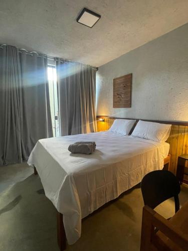 a bedroom with a large white bed and a window at Bangalôs Riviera do Patacho in Pôrto de Pedras