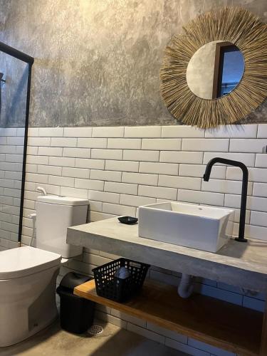 a bathroom with a sink and a toilet and a mirror at Bangalôs Riviera do Patacho in Pôrto de Pedras