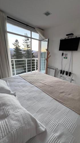 a white bed in a bedroom with a large window at Hostería Huinganco in Huinganco