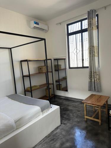 a bedroom with a bed and a table and a window at Bahari guesthouse in Nungwi