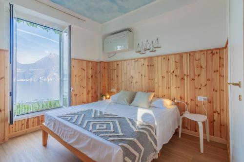 a bedroom with a bed and a large window at Villa La Perledina in Perledo