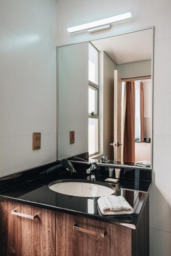 a bathroom with a sink and a large mirror at FRATELLI CORP APART HOTEL in La Paz
