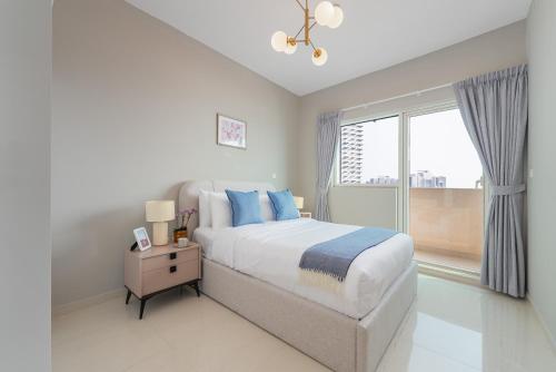 a white bedroom with a large bed and a window at Urban Chic - Marina Bay in Abu Dhabi