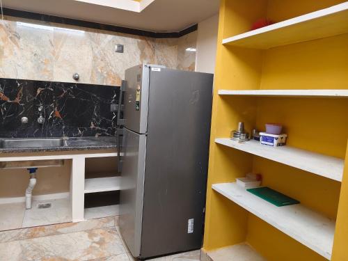 a kitchen with a stainless steel refrigerator and shelves at Ocean Wind Homestay in Pondicherry