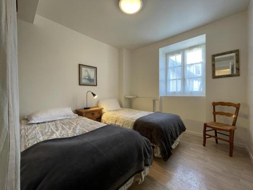 Zwei Betten in einem Zimmer mit einem Stuhl und einem Fenster in der Unterkunft Burusenia in Hasparren